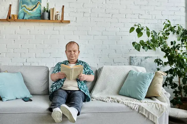 A man with inclusivity relaxes on a couch, engrossed in a book, enjoying a moment of peace. — Stock Photo