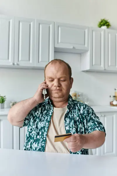 A man with inclusivity speaks on the phone while holding a credit card. — Stock Photo