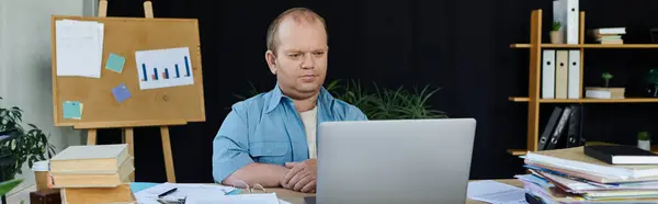 A man with inclusivity sits at a desk, working on his laptop in an office setting. — Stock Photo