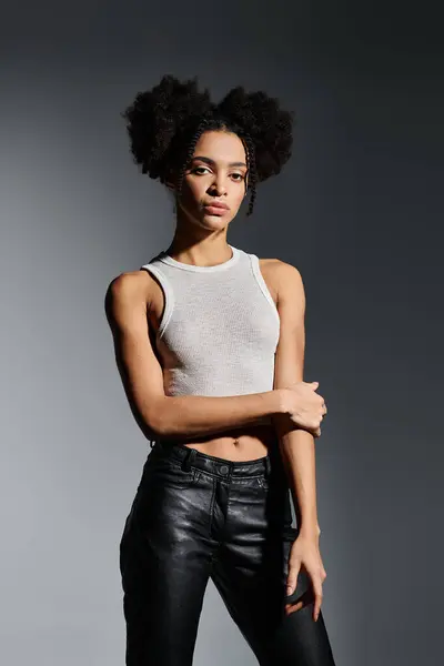 Una joven afroamericana con una camiseta blanca posa sobre un fondo gris. — Stock Photo