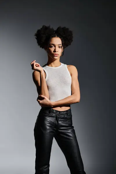 A young woman in a white tank top poses confidently on a grey backdrop. — Stock Photo