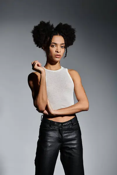 A young African American woman in a white tank top poses against a grey background. — Stock Photo