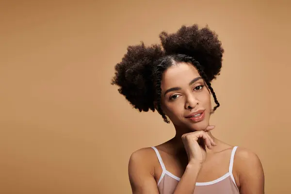 Uma jovem afro-americana com pele bonita e um sorriso radiante posa para um tiro de beleza contra um cenário bege. — Fotografia de Stock