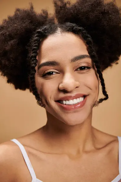 Uma jovem afro-americana sorri radiantemente contra um fundo bege. — Fotografia de Stock