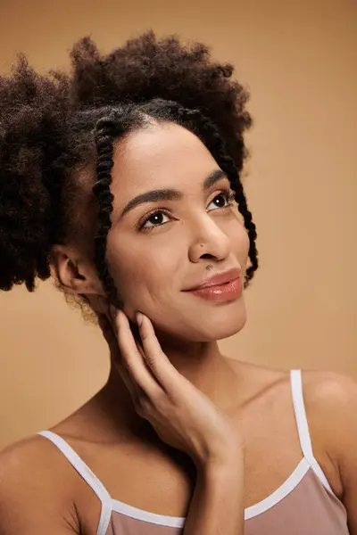 Uma jovem afro-americana com um sorriso radiante e poses de pele brilhante contra um pano de fundo bege. — Fotografia de Stock