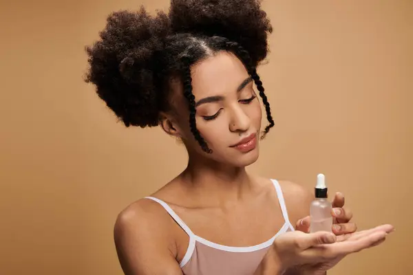 A young woman with curly hair holds a serum bottle in her hand. — Stock Photo