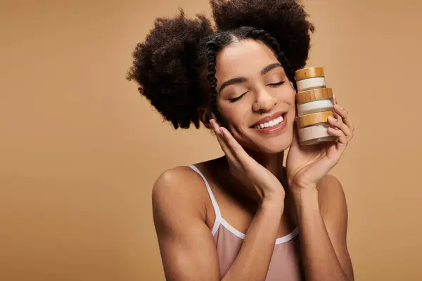 A young woman with a radiant smile and natural beauty holds a stack of jars against her face. — Stock Photo