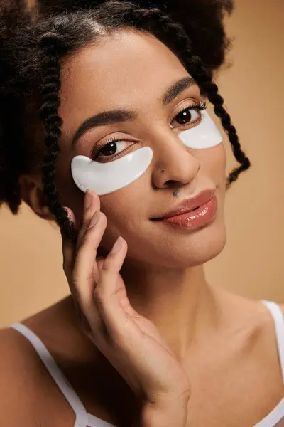 A young African American woman with eye patches on a beige background. — Stock Photo