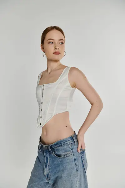 A young woman poses against a white background wearing a white top. — Stock Photo