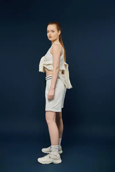 A young woman poses in white clothing against a deep blue backdrop. — Stock Photo