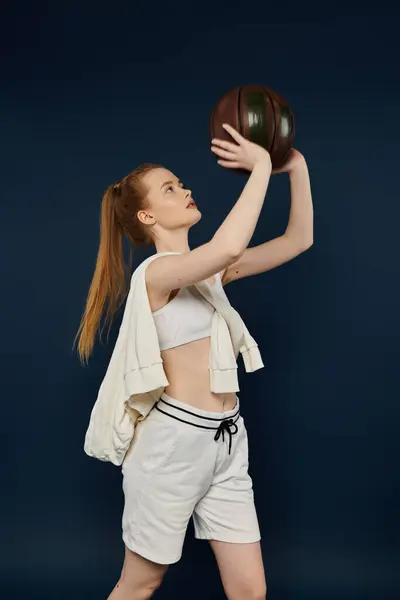 Young woman gracefully holds basketball against vibrant backdrop. — Stock Photo