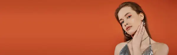 A beautiful young woman poses against a vibrant orange background. — Stock Photo