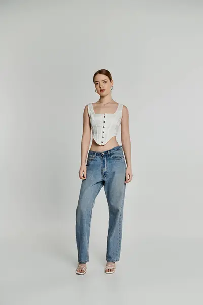 A young woman poses in a white corset and blue jeans. — Stock Photo