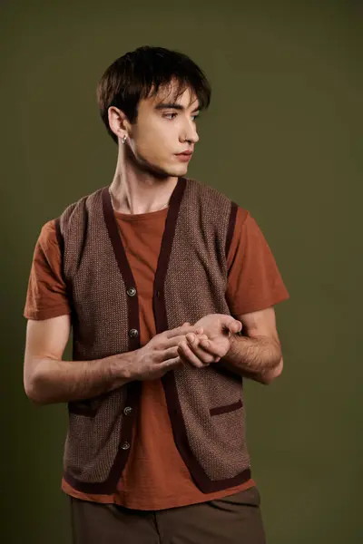 A man wearing a brown vest and orange t-shirt poses against a vibrant green backdrop. — Stock Photo