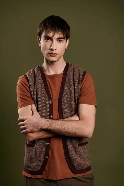 A man in a brown knitted vest poses against a green backdrop. — Stock Photo