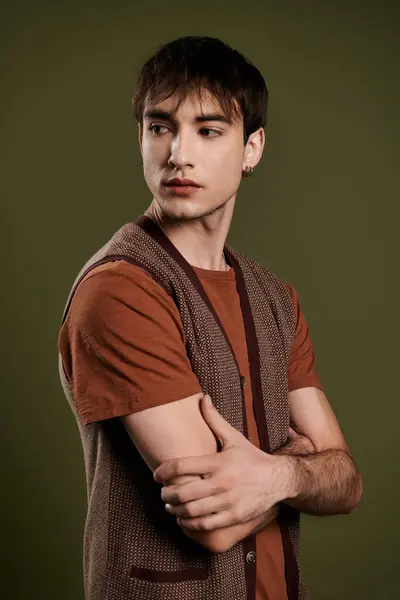 A handsome man in a brown vest and t-shirt poses against a vibrant green background. — Stock Photo