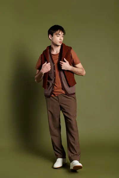 A man in a brown vest poses against a bright green backdrop. — Stock Photo