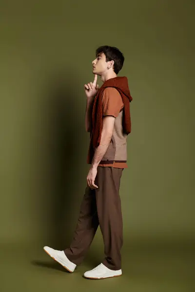 A man in a red sweater and brown pants poses on a vibrant green background. — Stock Photo