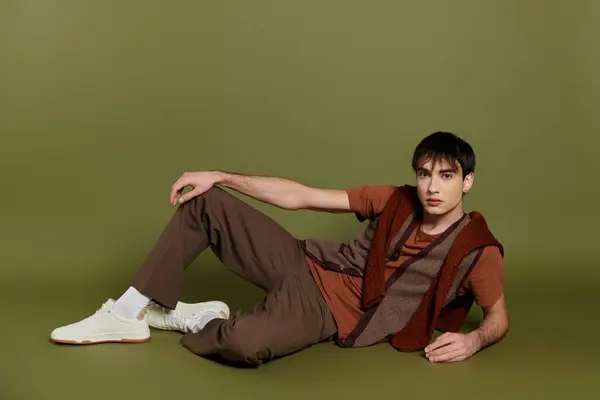 A stylish man wearing brown pants and a brown vest poses on a green backdrop. — Stock Photo