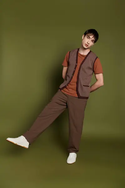 A man in a knit vest and brown pants poses against a green background. — Stock Photo