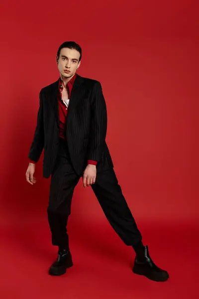 A man in a black suit stands on a red backdrop. — Stock Photo