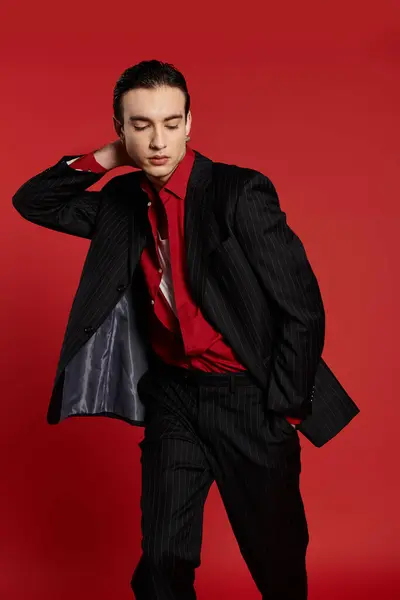 A man in a black suit poses against a red backdrop. — Stock Photo