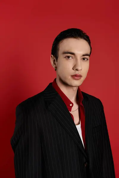 A man in a black pinstripe suit poses against a red backdrop. — Stock Photo