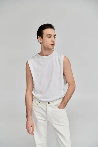 Un homme dans un débardeur blanc et un jean blanc pose sur un fond de couleur vive. — Photo de stock
