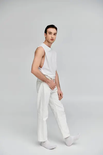 A man in white clothing poses against a gray background. — Stock Photo