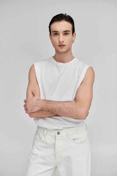 A stylish man in a white tank top and jeans poses against a bright backdrop. — Stock Photo