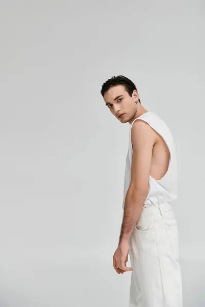 Un homme élégant pose dans un débardeur blanc et un pantalon sur un fond blanc. — Photo de stock