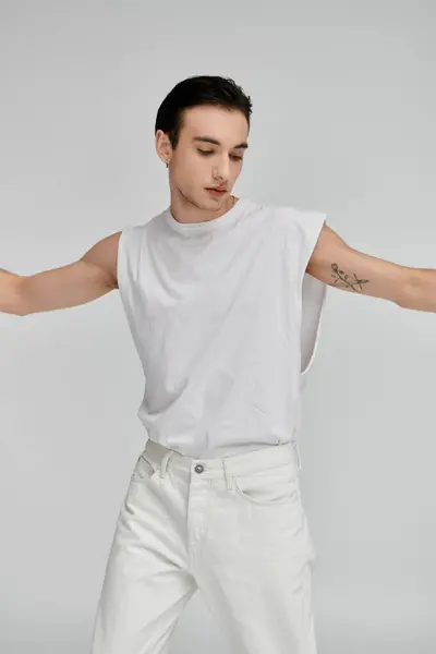 A stylish man poses in a white tank top and jeans against a colorful backdrop. — Stock Photo