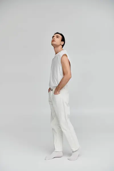 A man in all-white attire stands confidently against a neutral backdrop. — Stock Photo
