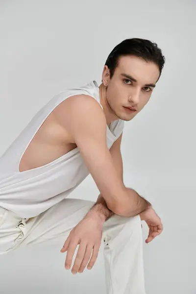 A young man in a white tank top and pants poses against a white backdrop. — Stock Photo