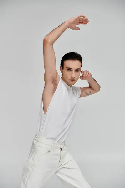 A man in a white tank top and jeans poses against a bright background. — Stock Photo