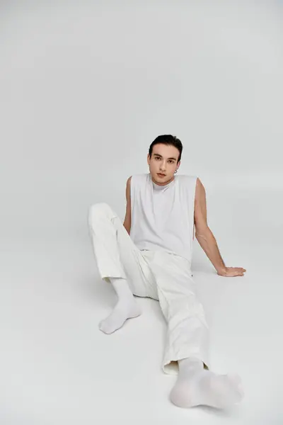 A man in all-white attire poses elegantly against a bright backdrop. — Stock Photo