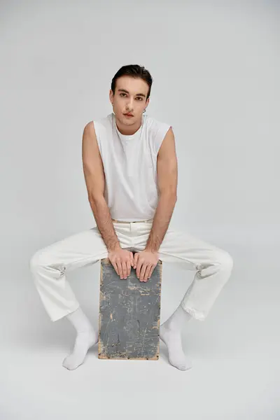 A man in white clothing poses on a wooden platform against a white backdrop. — Stock Photo