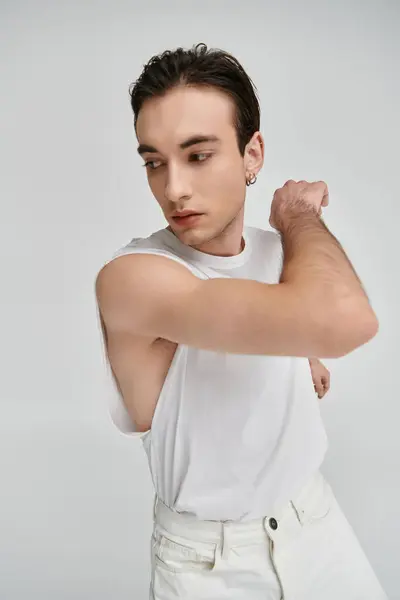 A handsome man in a white tank top and jeans poses against a white backdrop. — Stock Photo