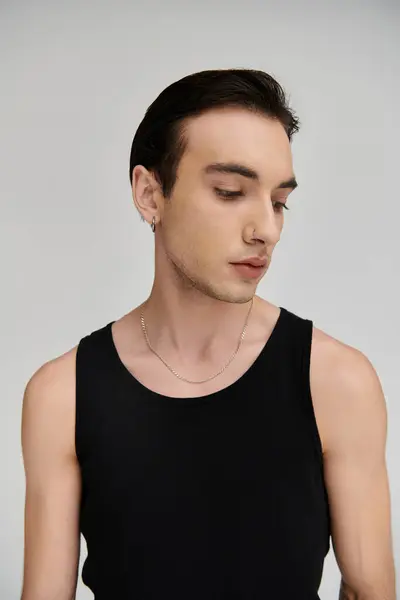 A young man with dark hair and a black tank top poses against a white backdrop. — Stock Photo