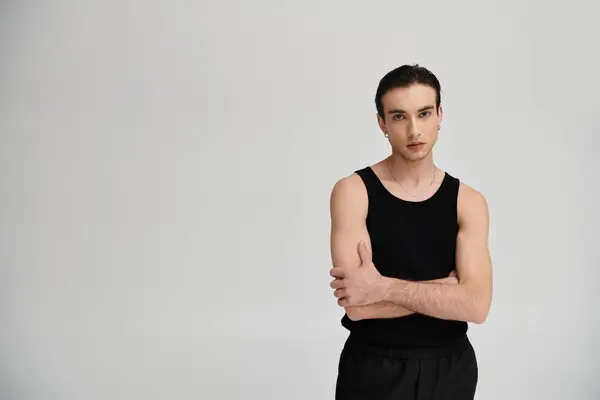A man in a black tank top poses with arms crossed against a vibrant backdrop. — Stock Photo
