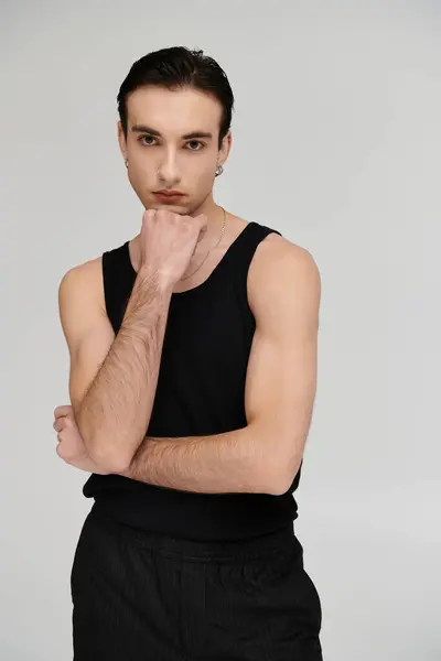 Stylish man in black tank top poses thoughtfully against vivid background. — Stock Photo