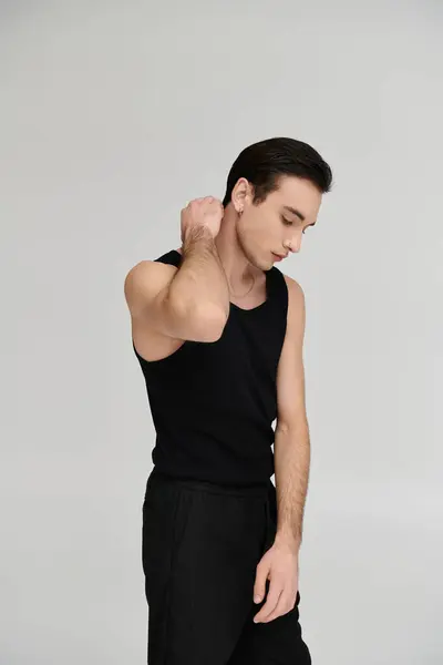 A young man in a black tank top and matching pants poses for a portrait against a white background. — Stock Photo