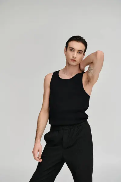 A man in a black tank top poses with his hand on his neck, standing against a white backdrop. — Stock Photo