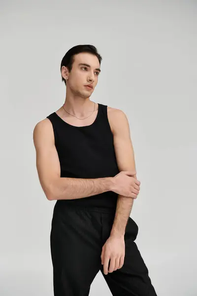 A handsome man wearing a black tank top and black pants poses against a white backdrop. — Stock Photo