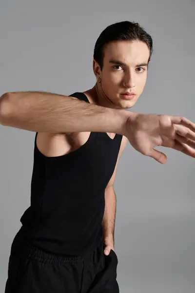 A handsome man in a black tank top poses against a gray background. — Stock Photo
