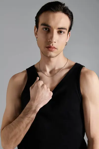 A handsome man in a black tank top poses against a gray background. — Stock Photo