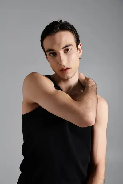 A handsome man in a black tank top poses against a grey backdrop. — Stock Photo