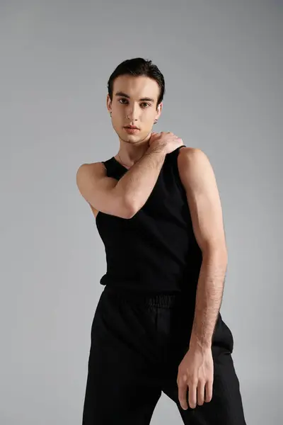 A confident man in black tank top against gray backdrop exudes style. — Stock Photo