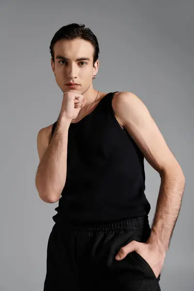 A handsome man poses in a black tank top against a gray backdrop. — Stock Photo