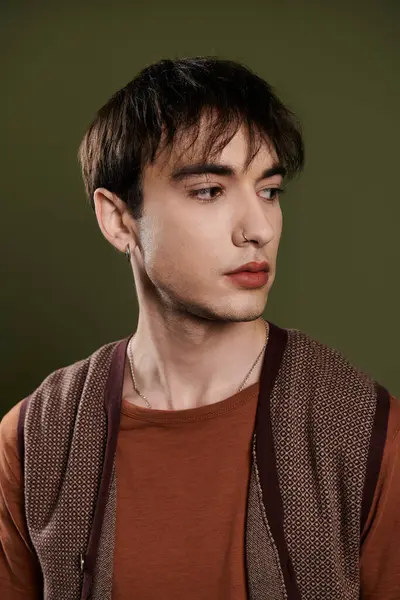 A handsome man poses against a vibrant green background, wearing a brown vest and a casual t-shirt. — Stock Photo
